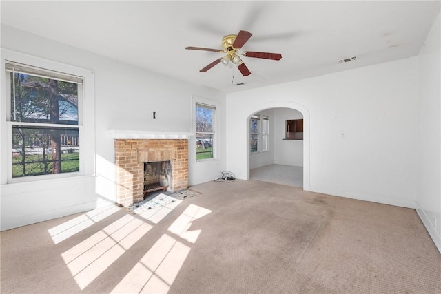 unfurnished living room with a fireplace, ceiling fan, and light carpet