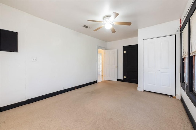 unfurnished bedroom featuring ceiling fan, light carpet, and a closet