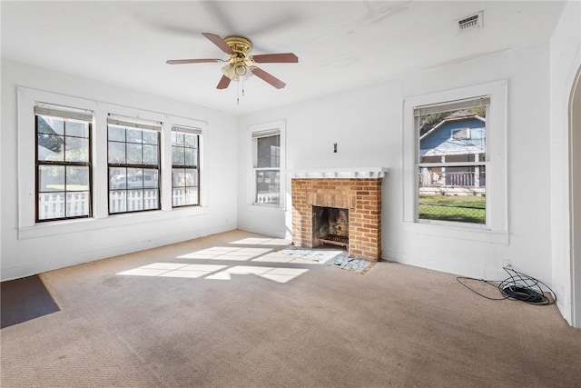 unfurnished living room with light carpet, a brick fireplace, and ceiling fan