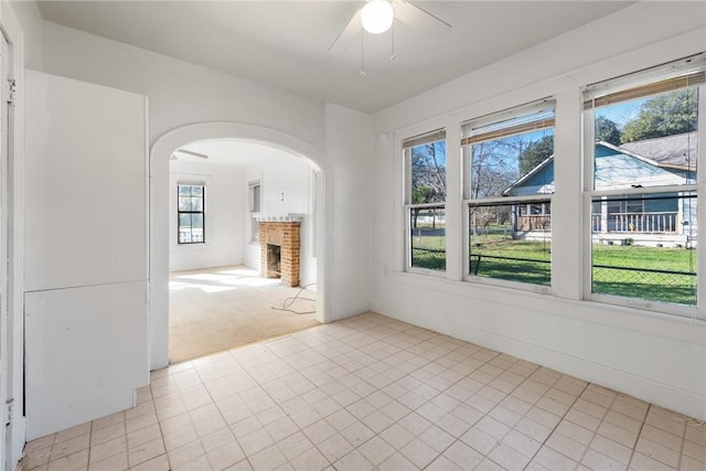 spare room with ceiling fan, light colored carpet, and a brick fireplace