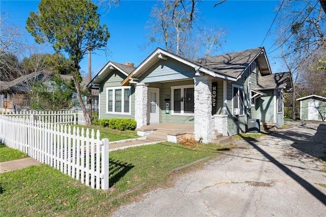 bungalow featuring a front yard, an outdoor structure, and covered porch