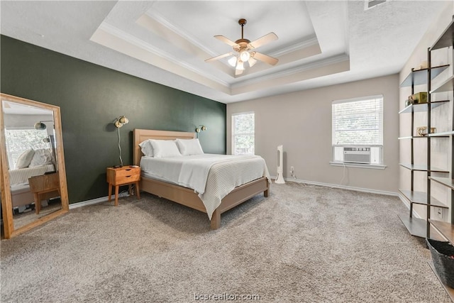 bedroom with carpet, a tray ceiling, multiple windows, and ceiling fan