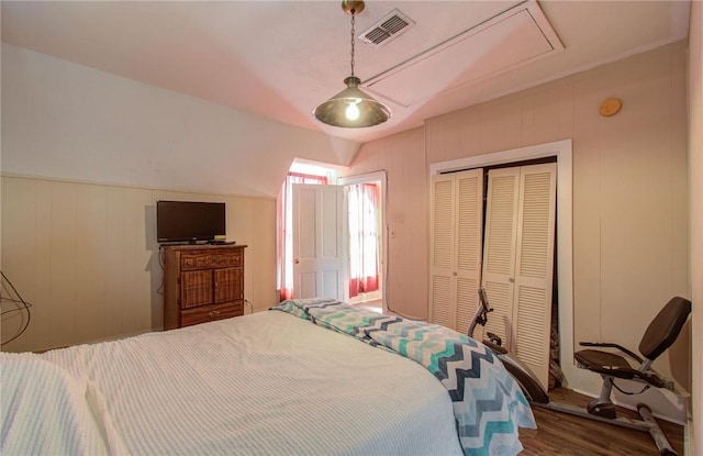 bedroom featuring hardwood / wood-style floors, a closet, and wooden walls