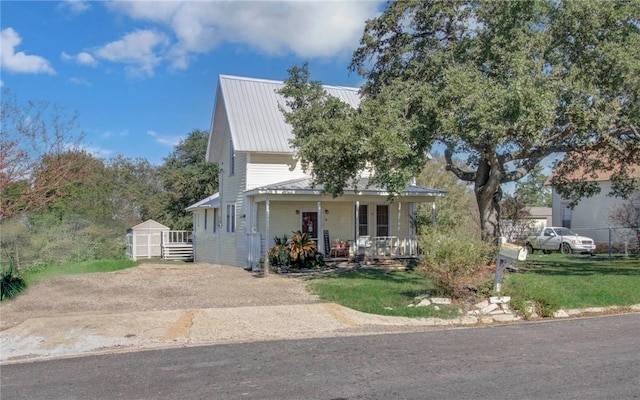 view of front of home with a front yard, a porch, and a shed