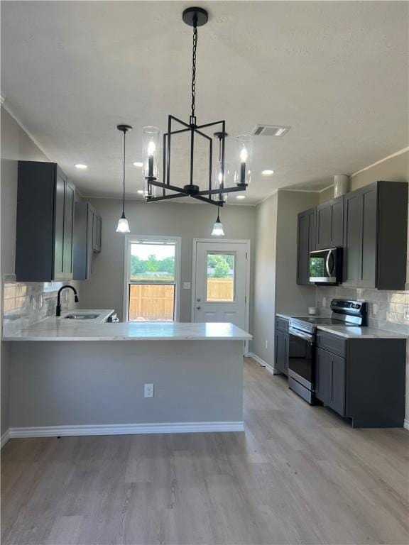 kitchen featuring tasteful backsplash, sink, light wood-type flooring, and appliances with stainless steel finishes