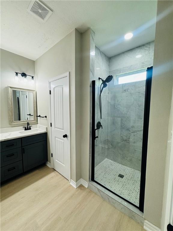 bathroom with tiled shower, vanity, and hardwood / wood-style flooring