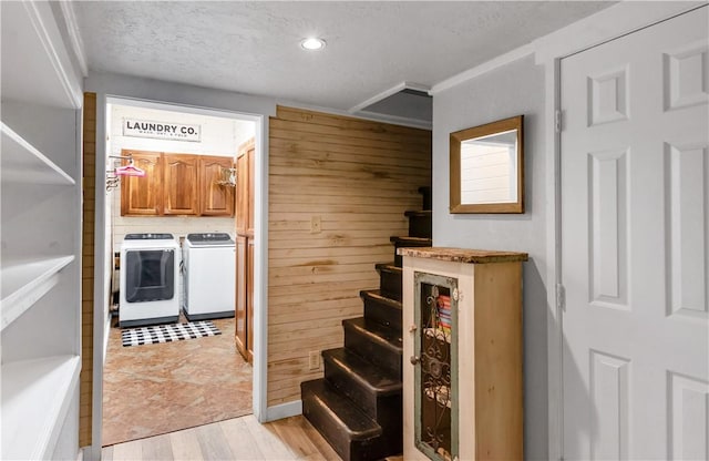 stairs with wood walls, washer and dryer, and a textured ceiling