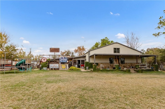 rear view of house with a playground, a trampoline, and a yard