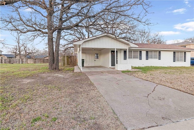 ranch-style home with driveway, brick siding, a front lawn, and fence