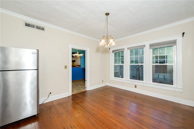 1004 S Magnolia St, Hearne, TX 77859 - unfurnished dining area featuring a chandelier, wood-type flooring, ornamental molding, and a textured ceiling