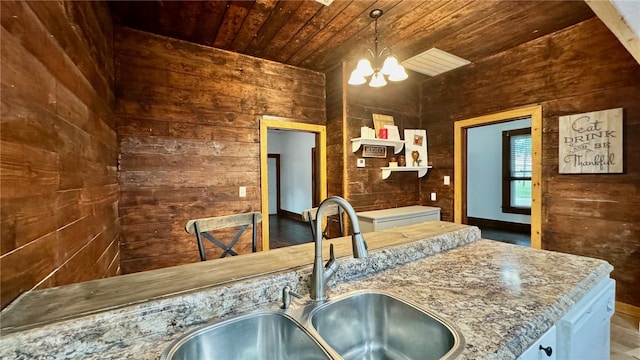 kitchen featuring sink, wood walls, a chandelier, decorative light fixtures, and wood ceiling