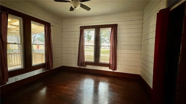 unfurnished room with wooden walls, plenty of natural light, and hardwood / wood-style floors