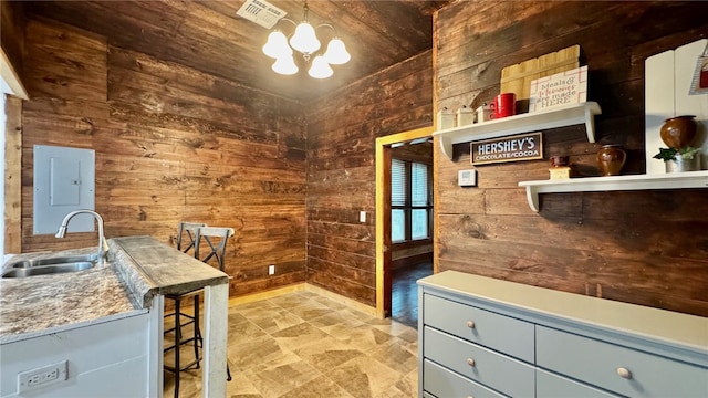 office area with sink, an inviting chandelier, and wood walls