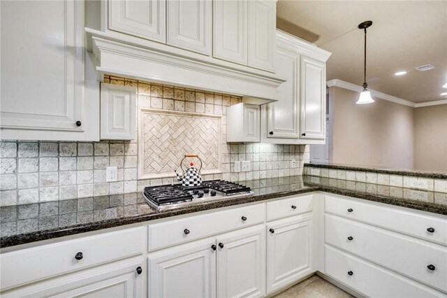 kitchen featuring ornamental molding, decorative light fixtures, tasteful backsplash, dark stone counters, and stainless steel gas stovetop