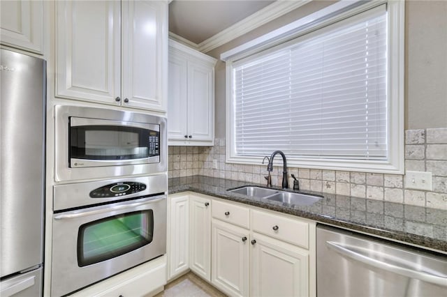 kitchen with a sink, dark stone countertops, tasteful backsplash, appliances with stainless steel finishes, and white cabinets