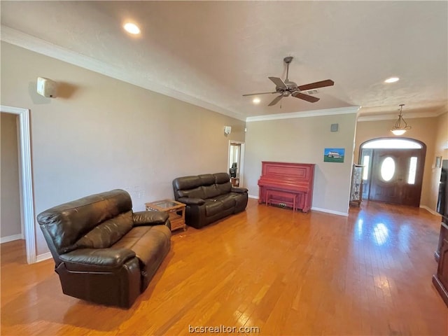 living room featuring hardwood / wood-style flooring, ceiling fan, and crown molding