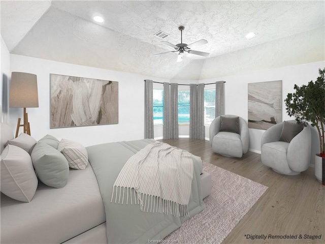 bedroom with lofted ceiling, ceiling fan, a textured ceiling, and light wood-type flooring