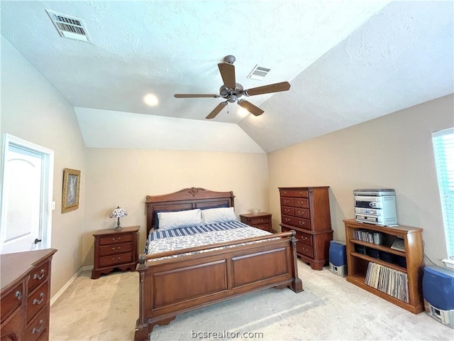 bedroom with a textured ceiling, light colored carpet, vaulted ceiling, and ceiling fan