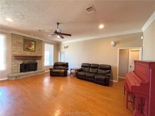 living room featuring a fireplace, crown molding, light hardwood / wood-style flooring, and ceiling fan