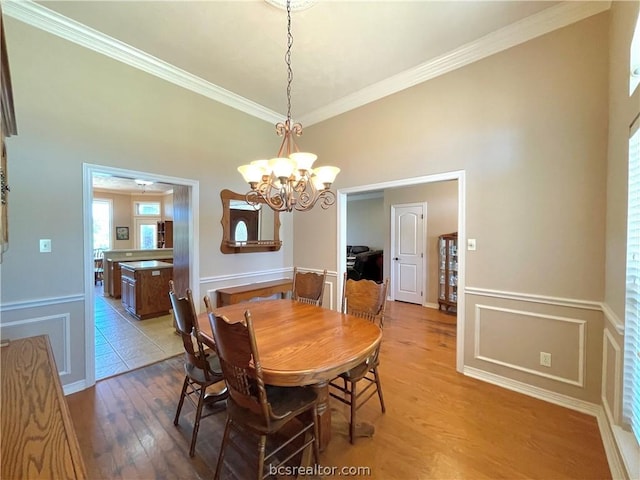 dining space with a notable chandelier, light wood-type flooring, and ornamental molding