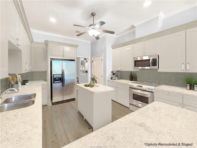 kitchen featuring appliances with stainless steel finishes, light stone counters, sink, light hardwood / wood-style flooring, and a center island