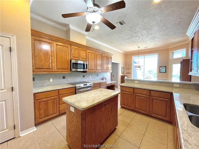 kitchen with crown molding, light tile patterned floors, hanging light fixtures, and appliances with stainless steel finishes