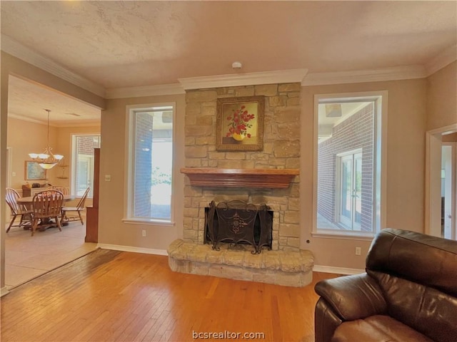 living room with a fireplace, wood-type flooring, an inviting chandelier, and crown molding