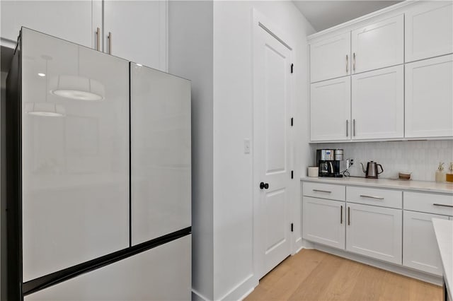 kitchen featuring backsplash, light hardwood / wood-style flooring, white cabinets, and fridge