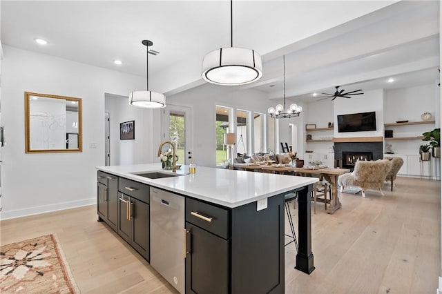 kitchen featuring dishwasher, pendant lighting, a center island with sink, and sink