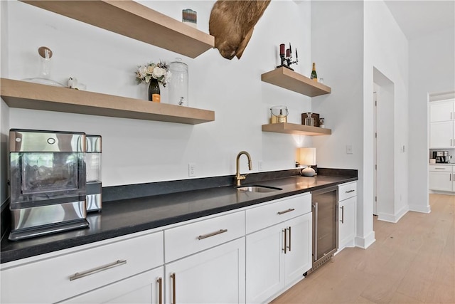 kitchen with light hardwood / wood-style floors, white cabinetry, sink, and wine cooler