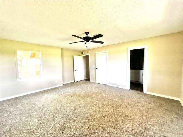 unfurnished bedroom with ceiling fan, carpet floors, ensuite bathroom, and a textured ceiling