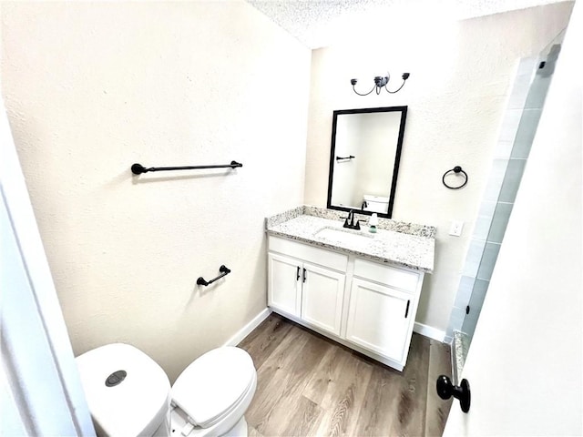 bathroom featuring vanity, wood-type flooring, a textured ceiling, and toilet