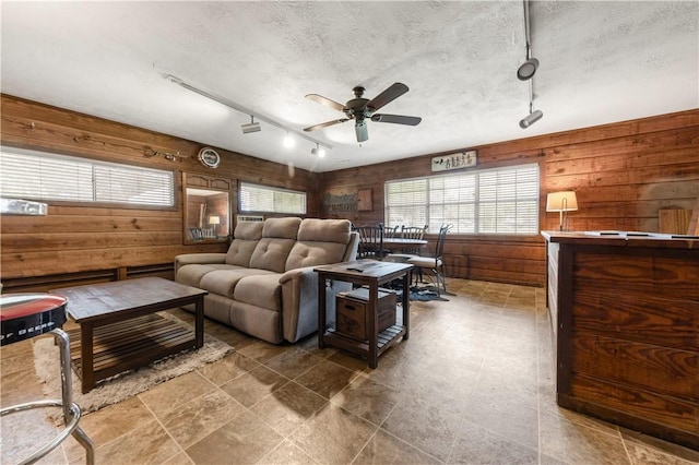 910 Briar Cliff Dr, Bryan, TX 77802 - living area with wood walls, track lighting, a ceiling fan, and a textured ceiling