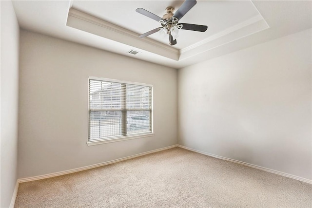 carpeted empty room featuring a raised ceiling, visible vents, crown molding, and baseboards