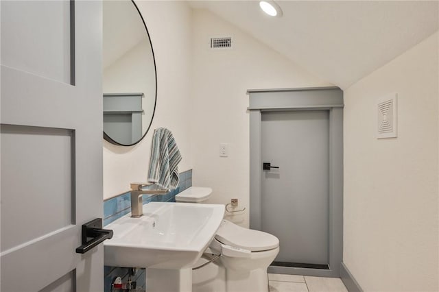 bathroom featuring sink, toilet, vaulted ceiling, and tile patterned flooring