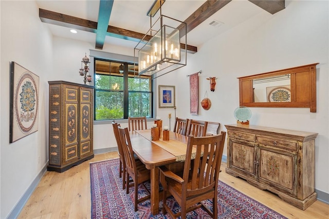 dining space with light wood-type flooring, coffered ceiling, a notable chandelier, and beam ceiling