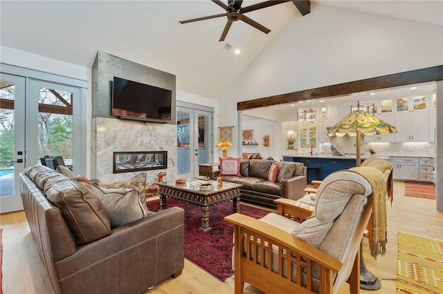 living room with light hardwood / wood-style flooring, french doors, a high end fireplace, beamed ceiling, and high vaulted ceiling