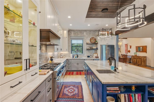 kitchen with white cabinetry, a kitchen island with sink, sink, high end appliances, and pendant lighting