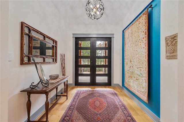 entryway with a notable chandelier, light hardwood / wood-style flooring, and french doors