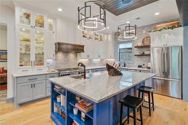 kitchen with a center island with sink, white cabinets, light stone countertops, and stainless steel fridge