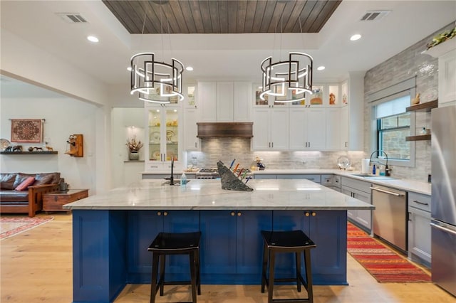 kitchen featuring a center island with sink, stainless steel appliances, and a tray ceiling