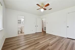 unfurnished bedroom featuring ceiling fan, connected bathroom, and hardwood / wood-style flooring