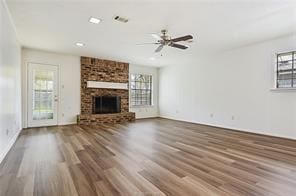 unfurnished living room with ceiling fan, a wealth of natural light, a fireplace, and hardwood / wood-style flooring