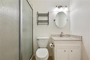 bathroom with toilet, vanity, and a shower with door