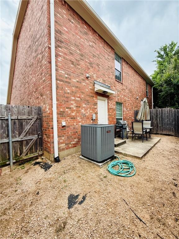 rear view of house with a patio, central air condition unit, brick siding, and fence