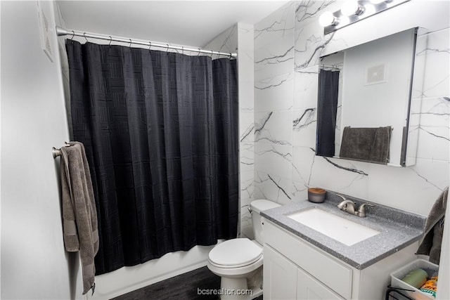 full bathroom with shower / bath combo, hardwood / wood-style floors, toilet, vanity, and tile walls