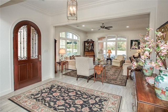 entrance foyer with ceiling fan, crown molding, and light hardwood / wood-style flooring