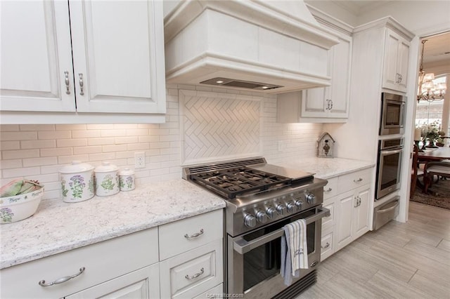 kitchen featuring custom exhaust hood, tasteful backsplash, light stone counters, white cabinetry, and stainless steel appliances