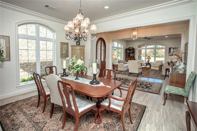 dining space with ceiling fan with notable chandelier, light wood-type flooring, and ornamental molding