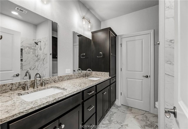 bathroom with a tile shower, vanity, and toilet